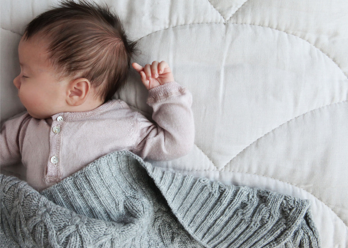 Nyfødt baby sover under tæppe, lyserød trøje, barselsgave inspiration